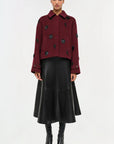 Woman wearing a burgundy jacket with black buttons and a black leather skirt on a white background