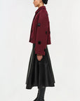 Person wearing a burgundy coat with black buttons on a white background