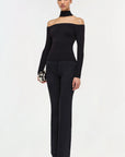 Woman wearing a black off-shoulder top and black pants on a white background