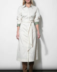 Woman wearing a long striped dress with a belt against a white background