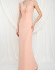 Woman wearing a long pink dress with a deep neckline on a white background