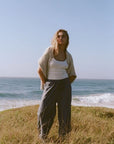 Woman standing on a grassy hill by the ocean with a clear sky.