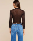 A woman shown from the back wearing a dark brown sheer long-sleeve mesh top and blue jeans against a solid beige studio background.