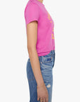 A woman shown in profile wearing a bright pink short-sleeve graphic T-shirt and blue jeans against a plain light gray studio background.