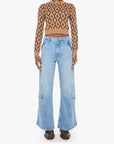 A model wearing a brown and beige patterned long-sleeve crop top paired with light blue wide-leg denim jeans and dark brown shoes, standing against a plain white background.