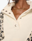 Woman wearing a cream-colored jacket with leopard print sleeves on a white background