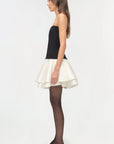 Isabelle Taffeta Knit Mini Dress on a model holding a black bag with a white background side