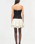Isabelle Taffeta Knit Mini Dress on a model holding a black bag with a white background back