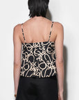 Person wearing a black and beige patterned top with thin straps on a white background