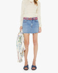 Woman wearing a cream sweater, denim skirt, and colorful headband on a white background