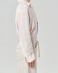 Model wearing a light-colored shirt with long sleeves on a plain background
