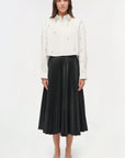 Woman wearing a white blouse and black pleated skirt on a white background