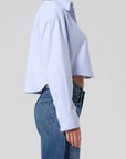 Person wearing a light blue shirt and jeans on a plain background