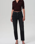Person wearing a burgundy cropped shirt and black jeans on a white background front view