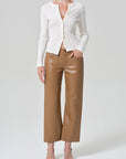 A model wearing a white long-sleeve button-front cardigan, brown wide-leg cropped pants, and beige strappy heels, photographed against a light gray studio background.