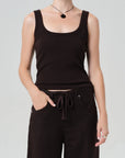 Person wearing a brown tank top and black pants on a light gray background