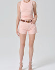Person wearing a pink sleeveless top and shorts on a white background