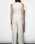 Person wearing a white sleeveless top and wide-leg pants against a plain background