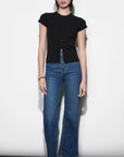 Woman wearing a black top and blue jeans against a white background