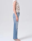 Person wearing light blue jeans and a beige top on a white background