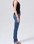 Person wearing blue jeans and a black top on a white background