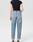 Person wearing light blue jeans and a black top on a white background
