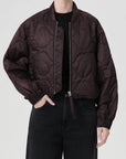 Person wearing a dark brown quilted jacket on a light gray background