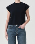 Person wearing a black sleeveless top and blue jeans on a plain background