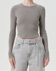 Person wearing a gray ribbed long-sleeve top and light gray jeans on a white background, front