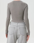 Person wearing a gray ribbed long-sleeve top and light gray jeans on a white background, back