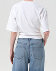 Person wearing a white t-shirt and light blue jeans against a plain background