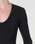 Black long-sleeve top worn by a person on a white background