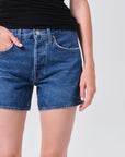 model wearing denim shorts with black shirt on a white background
