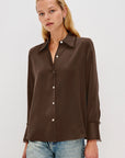 Woman wearing a brown button-up shirt and light blue jeans on a white background front