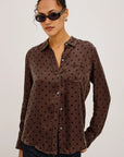 Woman wearing a brown polka dot shirt against a plain background