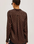 Person wearing a brown polka dot shirt on a plain background
