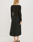 Woman wearing a black lace top and black skirt on a white background back view