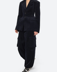 Person wearing a dark blue suit with cargo pants on a white background