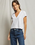 Woman wearing a white t-shirt and blue jeans against a plain background, size S