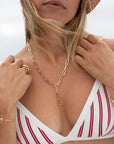 Woman wearing a gold chain necklace and bracelet, with a blurred background