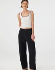 Woman wearing a white tank top and black pants on a white background