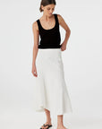 Woman wearing a black tank top and white skirt on a white background
