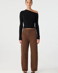 Woman wearing a black one-shoulder sweater and brown pants on a white background