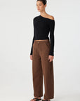 Person wearing a black off-shoulder top and brown pants on a white background