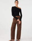 Woman wearing a black top and brown pants on a white background