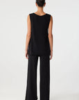 Person wearing a black sleeveless top and wide-leg pants on a white background, back