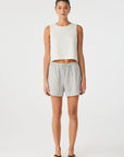 Woman wearing a white sleeveless top and gray shorts on a white background front