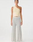 Woman wearing a one-shoulder top and striped pants on a white background