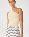 Woman wearing a one-shoulder cream top and a black and white patterned skirt on a white background