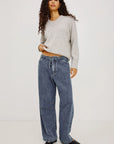Woman wearing a gray sweater and blue jeans on a white background